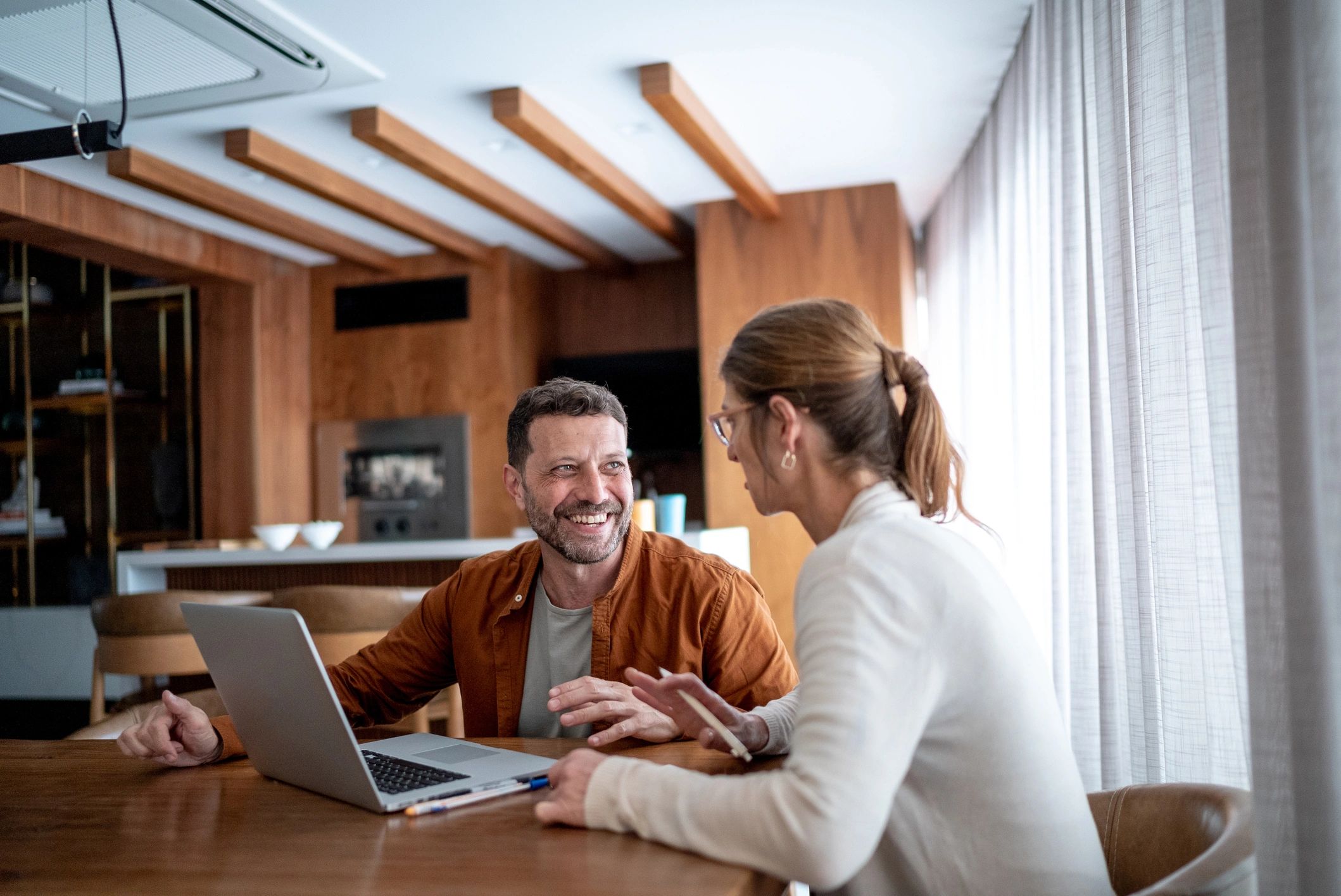 Homeowners talking together at a kitchen table with a laptop